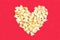 Top view of group salted popcorn mix with cheese popcorn pile on red table background in heart shape