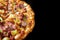 Top view of half Pizza with cheese ham bacon and pepperoni on isolated black background with hot steaming smoke. Food and cooking