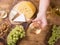 Top view of a hand holding a glass of white wine next to fresh grapes on a wooden table