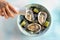 Top view of hand pouring vinegar dressing on fresh oysters