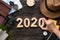 Top view hand putting 2020 happy new year number on wood table with adventure accessory item,holiday vacation planning