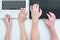 Top view of hands man and woman typing on two black and white laptops on white table