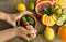 Top view hands pounding mint with pestle in mortar, citrus on dish