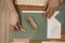 Top view of hands of unrecognizable woman hold grey, white sheets of paper with golden sealing wax, coil of jute rope.