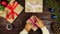 Top view hands wrapping christmas presents at wooden desk from above