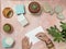 Top view of hands writing postcard with cactus, rocks, sea shelves and summer decorations on pink sandy table