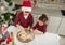 Top view of handsome children cooking together in the home kitchen during Christmas holidays. Charming preadolescent boy in Santa