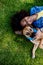 Top view of happy multiracial teenage girl with her dog lying in the grass. Concept of relationship between dog and