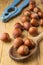 Top view of hazelnuts in wooden spoon and blue nutcracker on rustic table, with selective focus,