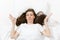 Top view of head of stress brunette young woman lying in bed with white sheet, pillow, blanket. Shocked tired female