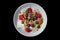 Top view of healthy cereal and oatmeal breakfast with berries and nuts in a white bow