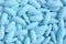 Top view of heap of ice blue oval shaped pills