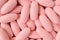 Top view of heap of light pink color oval shaped pills for background or banner