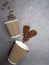 top view heart of coffee beans and paper disposable cups flat lay concrete background, mock up blank paper cups