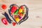 Top view of a heart made from pods of asparagus beans and fresh ripe vegetables on a wooden table