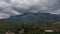 Top view of the hilly green area. Houses in the green forest. Timelapse. Overcast weather. Gray clouds.