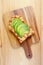 Top view of homemade grilled cheese toast topped with tomato and sliced avocado on wooden Breadboard