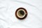 top view of hot coffee in brown ceramic cup on brown ceramic plate placed on blank clean tablecloths with soft light in the