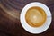 Top view of hot coffee cappuccino cup with saucer on wood texture abstract background.