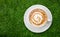 Top view of hot coffee latte art on green artificial grass background
