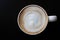 Top view of hot coffee latte cappuccino spiral foam in ceramic on dark background