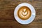 Top view of hot coffee latte cup with rosetta latte art milk foam on rustic wood table background.