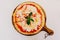 Top view of hot served Pizza Margherita on wooden plate with olive oil