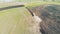 Top view of a huge field getting sown by a tractor