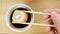 TOP VIEW: Human hand dips a sushi in a soy sauce cup