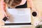 Top view of human hands, laptop keyboard, coffee, smartphone, on a wooden table