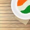 Top view illustration of Indian flag color rice in a plate on wooden background.