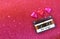 Top view image of colorful heart shape chocolates and audio cassette on red glitter background