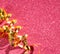 Top view image of curly golden ribbon over textured pink shiny background