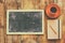 Top view image of empty blackboard next to cup of coffee and notebook, over wooden table. image with retro style filter