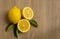 Top view image, Fresh yellow ripe lemon round fruit and half sliced fruits with green leaf on brown wooden table and copy space