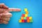 top view image of a male hand pointing to the top of wood blocks pyramid