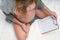 Top view image of pregnant woman holding birth plan checklist and pencil while sitting on her bed at home