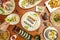 Top view image of sushi dishes, uramaki, wakame seaweed, wasabi, salmon, red tuna, hand with chopsticks, assorted dim sum and
