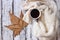 Top view image of white cozy knitted sweater with to cup of coffee and autumn leaves on a wooden table