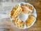 Top view image, a white plate of yellow brown crunchy and crispy roti or bolloon bread fired Indian style snack, on wooden table