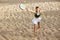 Top view image of young woman playing paddle, beach tennis, hitting ball with racket in motion. Competition