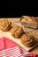 Top view of individual plum cakes on rustic wooden table with red dishcloth, black background