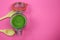 Top view on isolated glass preserving jar with green spinach powder and two wood spoons, pink background. copy space for text.