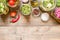 Top view jars with canned vegetables, raw ingredient and seasonings on wooden kitchen table. Food preservation and conservation