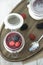 Top view of jars of yogurt with jam and berries on a tray on the table