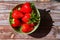 Top view of juicy sunkissed strawberries in a green bowl on a wooden surface