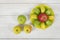 Top view of juicy yellow and green apples placed around the whole apple on a saucer.