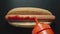 TOP VIEW: Ketchup bottle pouring tomato sause on a hot dog with sausage