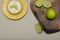 Top view of a key lime tartlet on a plate with key lime fruits on a wooden board