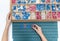 Top view of kids hands building words by using colored Montessori movable alphabet from the wooden tray on blackboard